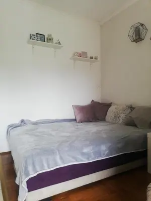 a bed in a bedroom with two shelves on the wall at App Milica do akva parka Raj in Vrnjačka Banja