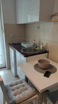 a kitchen with a sink and a counter with two chairs at App Milica do akva parka Raj in Vrnjačka Banja