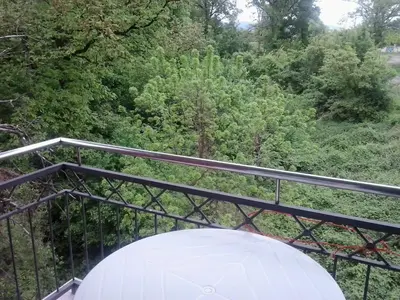 a white umbrella on a balcony with trees at App Milica do akva parka Raj in Vrnjačka Banja
