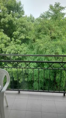 a balcony with a white chair and a view of trees at App Milica do akva parka Raj in Vrnjačka Banja