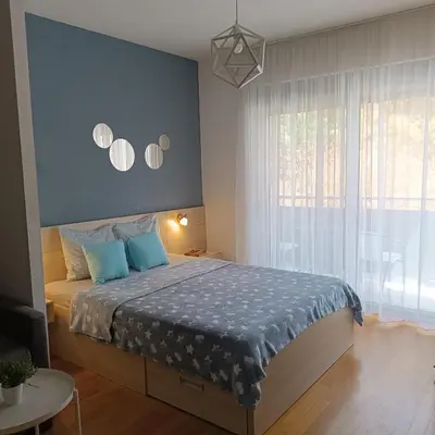 a bedroom with a bed with a blue wall at Apartments Karamarković in Vrnjačka Banja