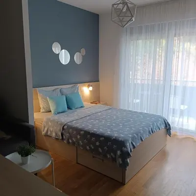 a bedroom with a bed with a blue comforter at Apartments Karamarković in Vrnjačka Banja