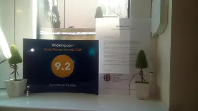 a sign sitting on a table next to two plants at Studio Dunja in Vrnjačka Banja