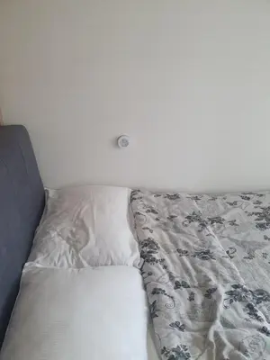 an unmade bed in a room with a white wall at Apartman 