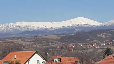 a village with snow covered mountains in the background at Apartman 