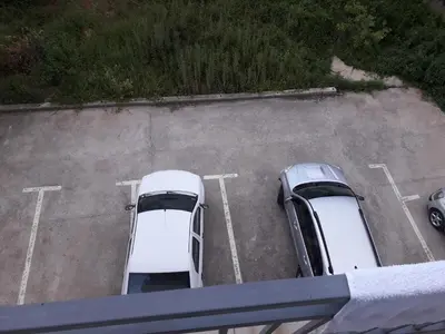 two white cars parked in a parking lot at Apartman 