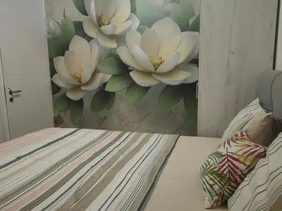 a bedroom with a mural of white flowers on the wall at Apartment Holiday in Vrnjačka Banja