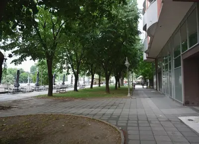 a sidewalk in front of a building with trees at Trident Apartments 2 in Niš