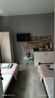 a room with two beds and a tv and a table at Happy Star in Niš