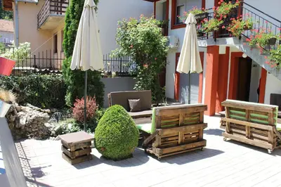 an outdoor patio with umbrellas and chairs and bushes at Guest Accommodation Zone in Niška Banja