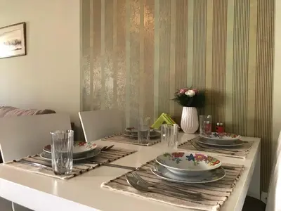 a dining room table with plates and utensils on it at Apartman Sofia in Vrnjačka Banja
