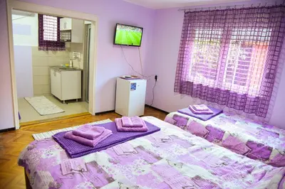 a purple bedroom with two beds with towels on them at PRENOĆIŠTE PILOT in Niš