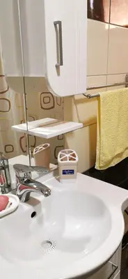 a bathroom with a white sink and a mirror at Apartman NADA in Vrnjačka Banja