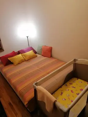 a bed with colorful pillows on it in a room at Apartman NADA in Vrnjačka Banja