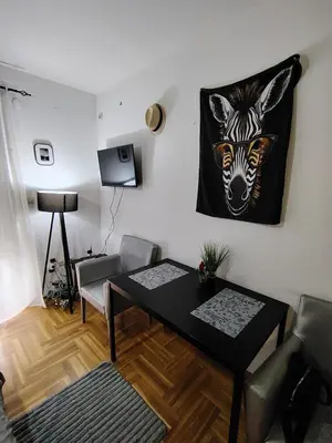 a living room with a table and a painting of a zebra at Studio ARIES in Vrnjačka Banja