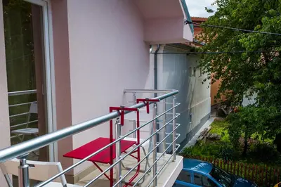 a group of red chairs on a balcony at Apartmani 