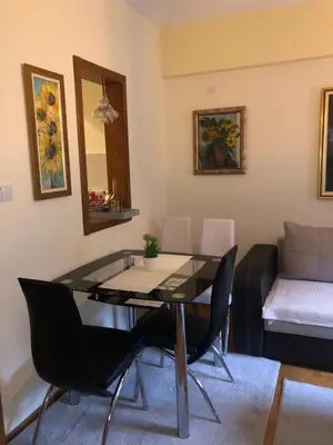 a living room with a glass table and chairs at Sunčani Apartman in Brzeće