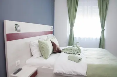 a bedroom with a white bed with a remote control on it at Apartmani Banja SPA in Vrnjačka Banja
