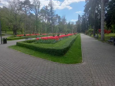 a park with red and pink flowers and a sidewalk at Nidza Vranjanac in Vrnjačka Banja