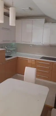 a kitchen with white cabinets and a white table and chairs at Apartments Holiday in Vranje