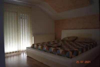 a bedroom with a bed in a room with windows at Apartments Holiday in Vranje
