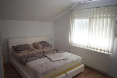 a white bedroom with a bed with a window at Apartments Holiday in Vranje