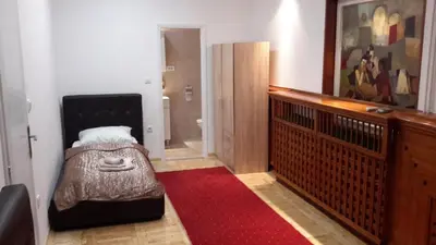 a hallway with a red rug and a room with a bed at Fortezza rooms in Niš