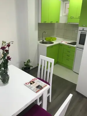 a kitchen with green cabinets and a white table and chair at La Apartamento in Jagodina