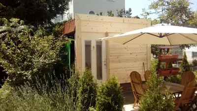 a patio with an umbrella and a wooden shed at Kuća Popović Apartments in Niš