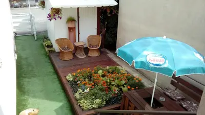 a patio with a blue umbrella and chairs and flowers at Kuća Popović Apartments in Niš