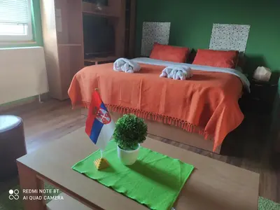 a room with a bed with orange sheets and a table at Sweet dreams in Zaječar