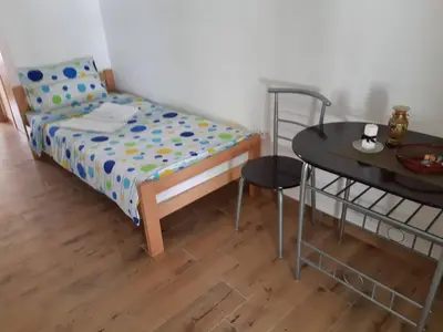 a small bedroom with a bed and a table at Apartmani Gmitrovic in Rtanj