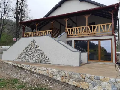 a house with a stone wall in front of it at Apartmani Gmitrovic in Rtanj