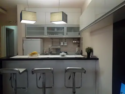 a kitchen with a counter with three bar stools at Apartman ZVEZDA in Jagodina