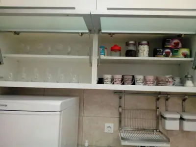 a kitchen with white shelves with cups and dishes at Apartman ZVEZDA in Jagodina