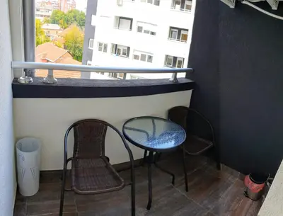 a balcony with two chairs and a table and a window at DM apartment in Niš