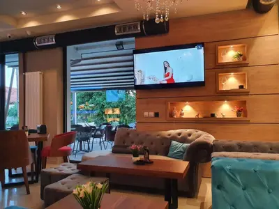 a living room with a couch and a tv on a wall at Family Apartments in Zaječar