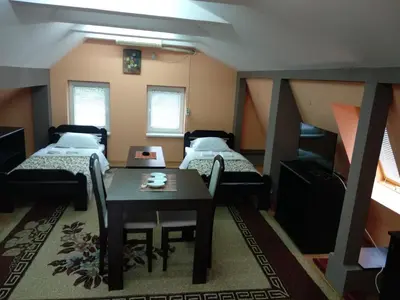 a room with two beds and a table and a table and chairs at Small Apartment at center of the city in Niš