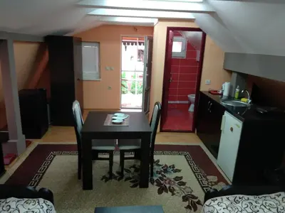a dining room with a table and a kitchen at Small Apartment at center of the city in Niš