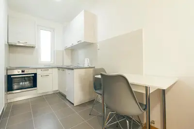 a kitchen with white cabinets and a table and chairs at Tea Studio Apartments in Niš