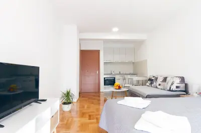 a white living room with a couch and a television at Tea Studio Apartments in Niš