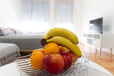 a bowl of fruit with apples oranges and bananas at Tea Studio Apartments in Niš