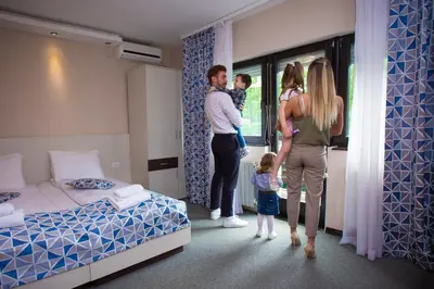 a family standing in a hotel room looking out the window at Hotel Danica in Vrnjačka Banja