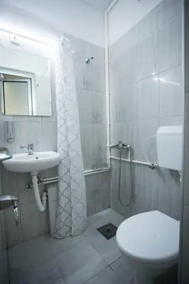 a bathroom with a shower and a toilet and a sink at Apartmani DiO in Niš