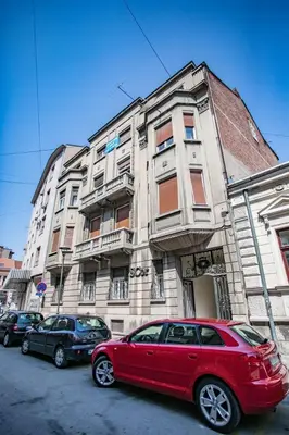a red car parked in front of a building at Apartmani DiO in Niš