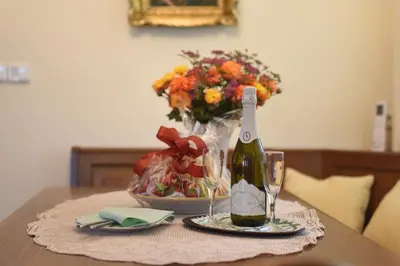 a table with a bottle of wine and a vase of flowers at Apartmani Nik Lux in Vrnjačka Banja