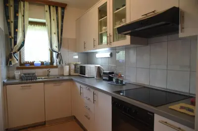 a kitchen with white cabinets and a black appliances at Apartmani Nik Lux in Vrnjačka Banja