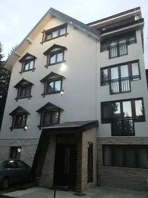 a white building with black windows at Apartmani Nikola u vili Semeteš in Kopaonik