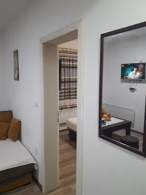 a mirror on a wall next to a living room at Apartmani Nikola u vili Semeteš in Kopaonik