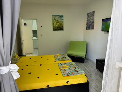 a bedroom with a yellow bed and a green chair at Mitić Apartmani 1 in Niš